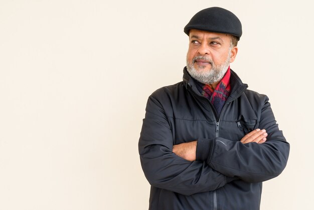 Portrait of handsome bearded Indian man against plain wall