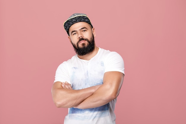 Portrait of handsome bearded man in cap looking at camera