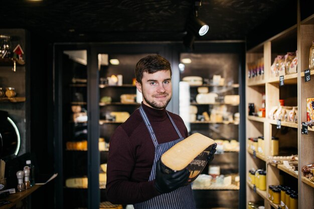 Portrait of handsome bearded man sniffing old cheese in shop