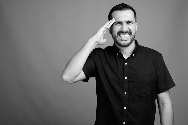 Portrait of handsome bearded Persian man wearing black shirt on gray in black and white