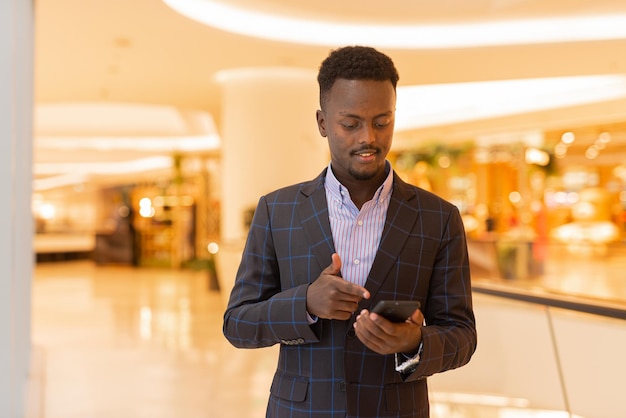 Portrait of handsome black businessman using mobile phone