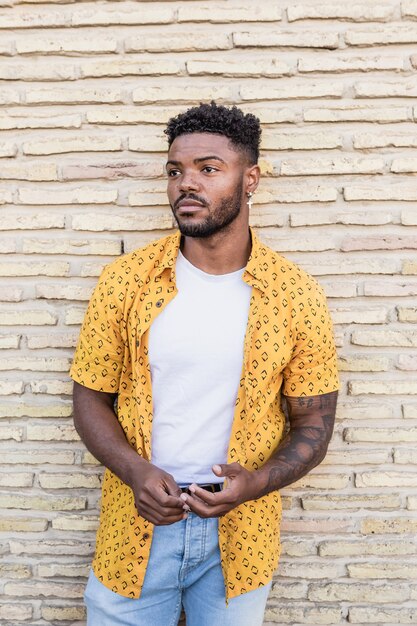 Photo portrait of a handsome black man smiling with a brick background