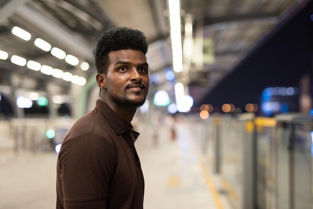 Portrait of handsome black man at train station during night