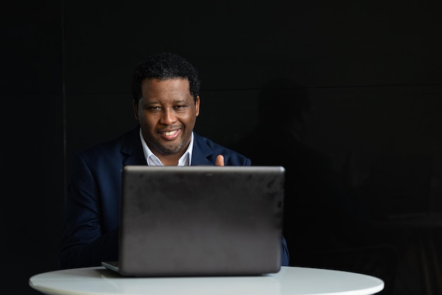 앉아있는 동안 양복을 입고 랩톱 컴퓨터를 사용하는 잘 생긴 흑인 남자의 초상화