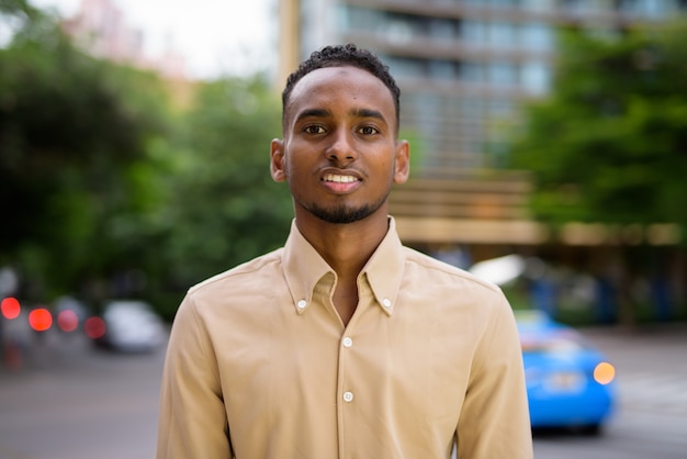 Photo portrait of handsome black young african businessman wearing casual clothes outdoors in city