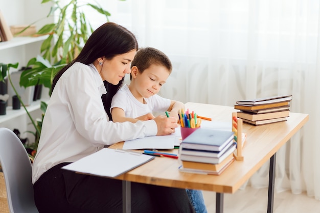 Portrait of handsome boy at workplace with his tutor sitting near by and telling something