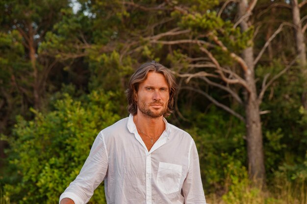 Portrait of handsome brutal man with long hair at sunset the blue eyes an easy bristle he is dressed