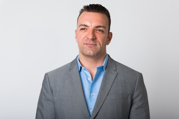 Portrait Of Handsome Businessman In 30s Wearing Suit Isolated Against White wall