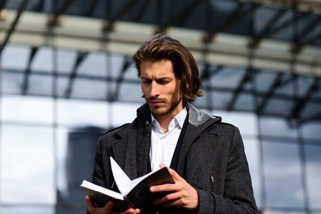 Photo portrait of an handsome businessman holding a book in the street