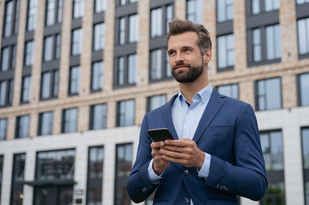 Foto ritratto di un bell'uomo d'affari che tiene in mano la comunicazione del telefono cellulare online business di successo