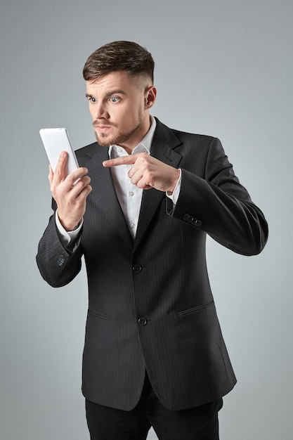 Portrait of a handsome businessman making phone call against grey background