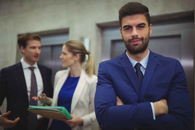 Portrait of handsome businessman standing with arms crossed