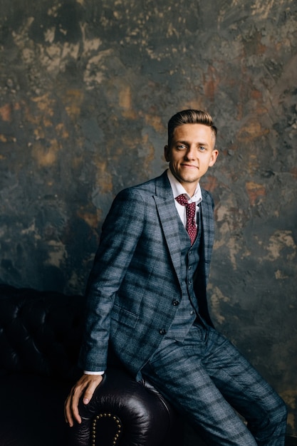 Portrait of a handsome businessman in suit on a luxury vintage leather sofa