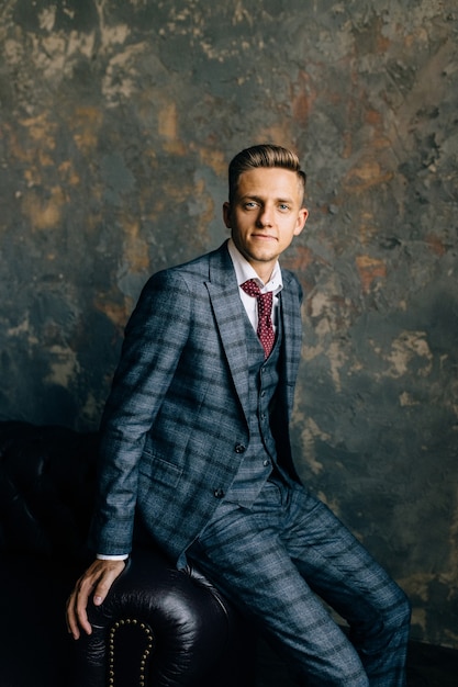 Portrait of a handsome businessman in suit on a luxury vintage leather sofa