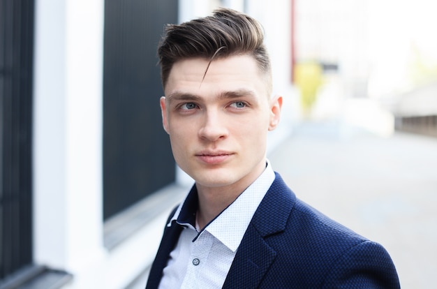 Portrait of a handsome businessman in a suit standing outside a city building