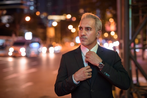 Portrait of handsome businessman wearing suit in city at night