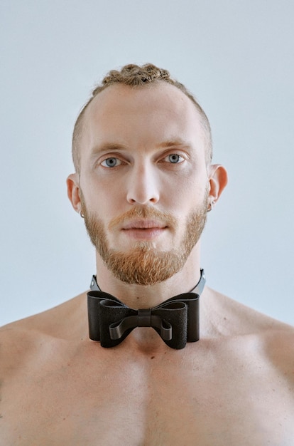 Portrait of handsome caucasian athletic young man topless in leather bow tie Fitness bodybilding