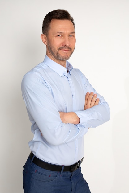 Portrait of handsome caucasian office worker man 40-44 years with arms crossed posing at camera on white background in shirt, looking confident and affable. Copy space. Business concept. Studio shot