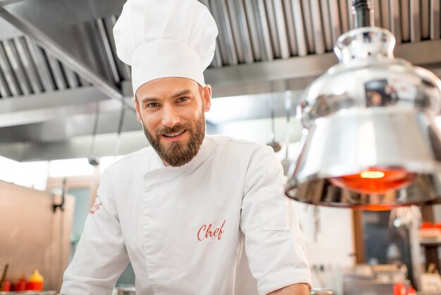 Портрет красивого шеф-повара в униформе на кухне ресторана