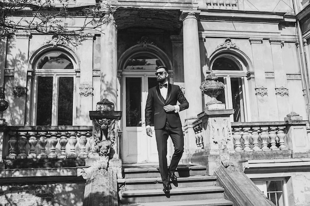 Portrait of handsome Chinese young man in light blue suit and white undershirt walking and looking away with modern city buildings background in sunny day side view of confident businessman