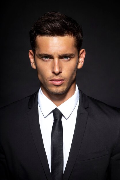 portrait of a handsome confident businessman wearing suit standing isolated on black