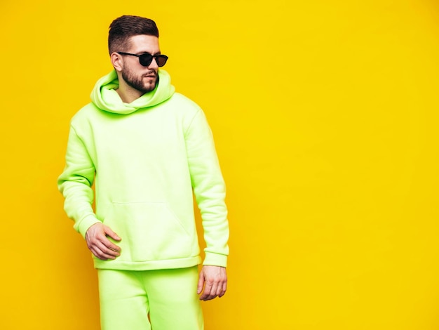 portrait of handsome confident model sexy stylish man dressed in yellow hoodie with no logo clothes branding mockup design template for casual sportswear fashion male isolated in studio
