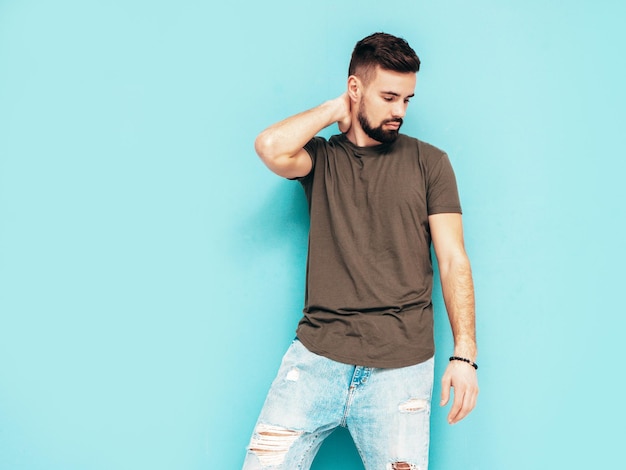 Portrait of handsome confident stylish hipster lambersexual modelMan dressed in Tshirt and jeans Fashion male isolated on blue wall in studio