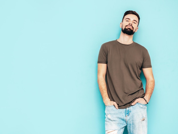 Portrait of handsome confident stylish hipster lambersexual modelMan dressed in Tshirt and jeans Fashion male isolated on blue wall in studio