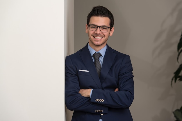 Photo portrait of handsome confident young businessman standing arms crossed