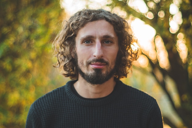 Portrait of a handsome curly-haired guy on the nature