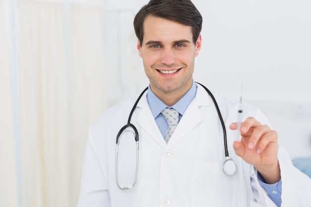 Portrait of a handsome doctor holding an injection