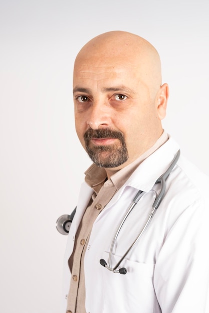 Portrait of handsome doctor. Wearing white uniform with stethoscope. Isolated light gray background.