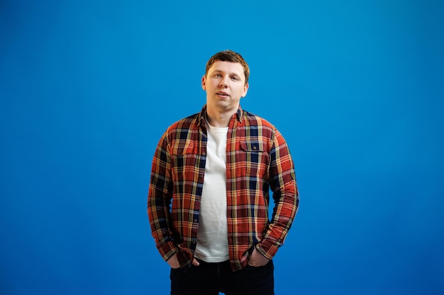 Portrait of handsome european man in shirt looking at camera standing on blue studio background