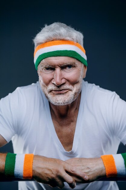 Portrait of a handsome gray haired senior man with a sports headband. Sport and health care concept