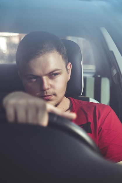 Foto ritratto di un bel ragazzo alla guida della sua auto