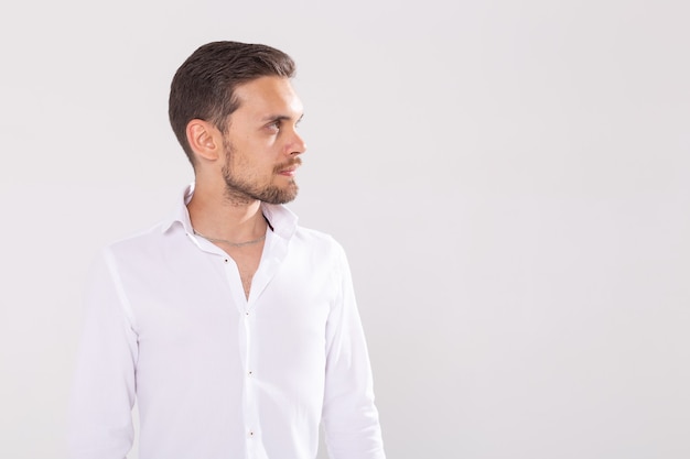 Portrait of handsome happy young man in casual shirt standing against white background