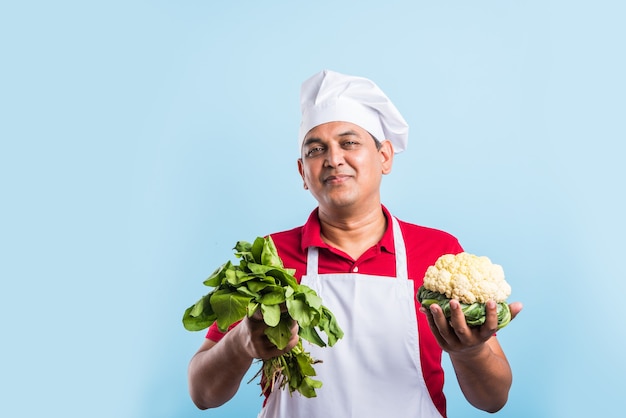 Portrait of handsome Indian male chef posing while doing activities