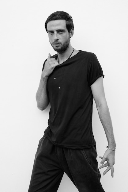 Portrait of handsome man against white wall outdoors in black and white