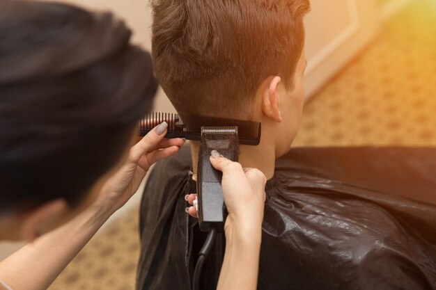 Photo portrait of handsome man in barbershop. barber working with electric razor, sunlight