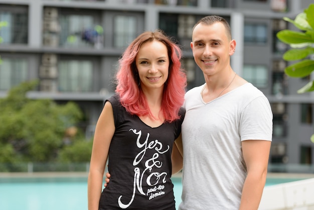Photo portrait of handsome man and beautiful woman with pink hair as couple together in the swimming pool area outdoors
