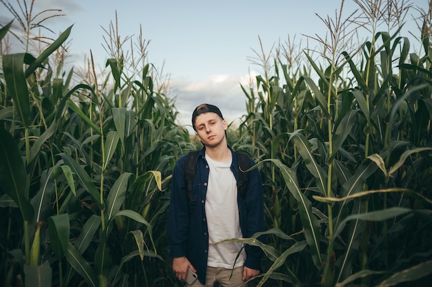 Portrait of a handsome man in casual casual clothes stands on a field with corn