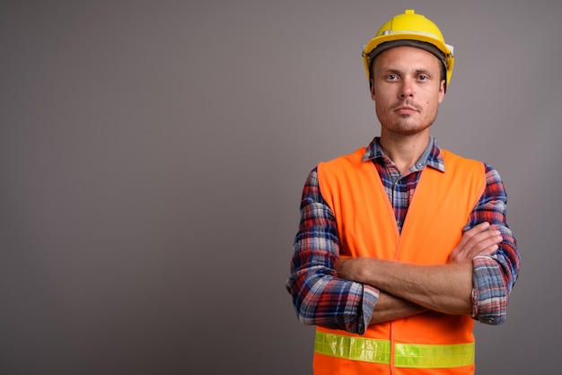 Portrait of handsome man construction worker on gray