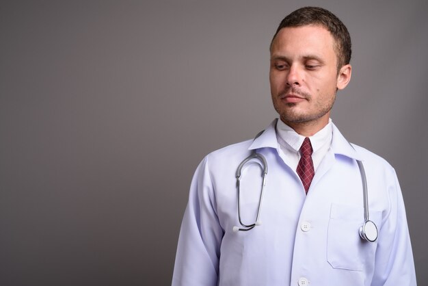 Portrait of handsome man doctor on gray