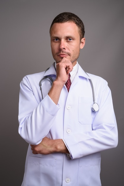 Portrait of handsome man doctor on gray