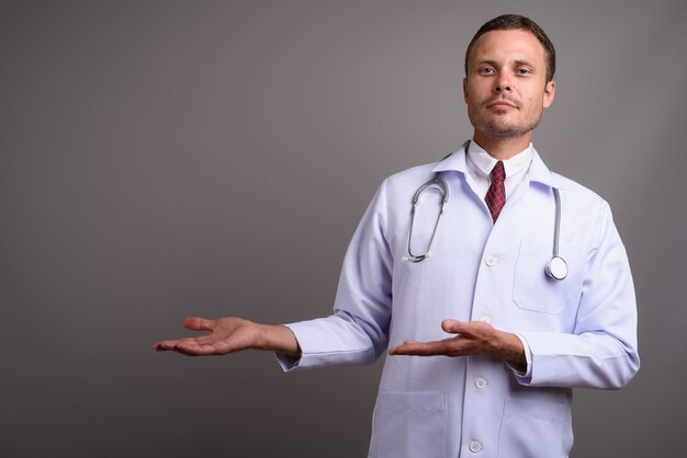 Portrait of handsome man doctor on gray