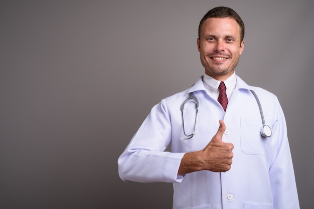 Portrait of handsome man doctor on gray