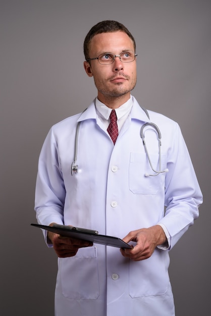 Portrait of handsome man doctor on gray