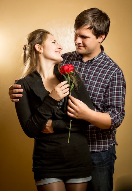 Портрет красивого мужчины, дающего красную розу подруге
