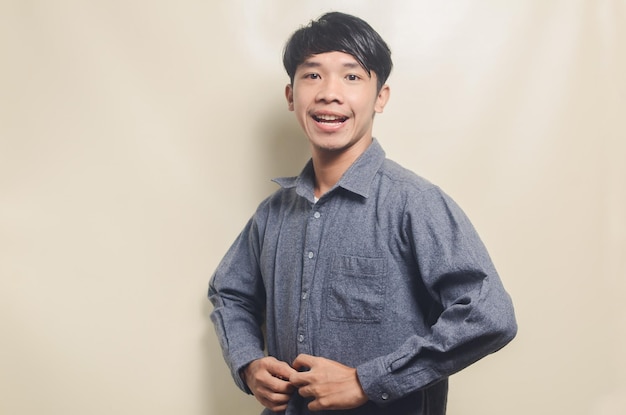 Portrait of handsome man in gray buttoning his shirt