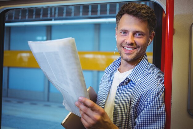 Portrait of handsome man holding newspaper while listening music